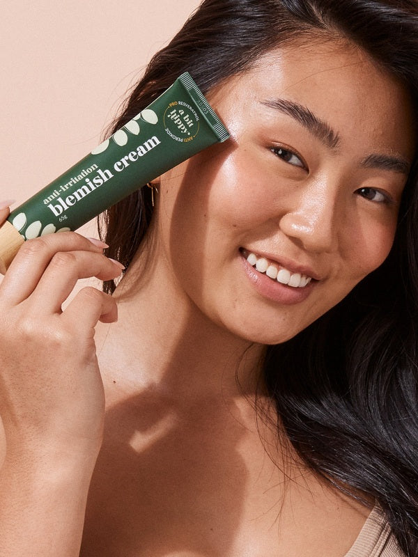 A bit Hippy Blemish Cream held beside a woman's face