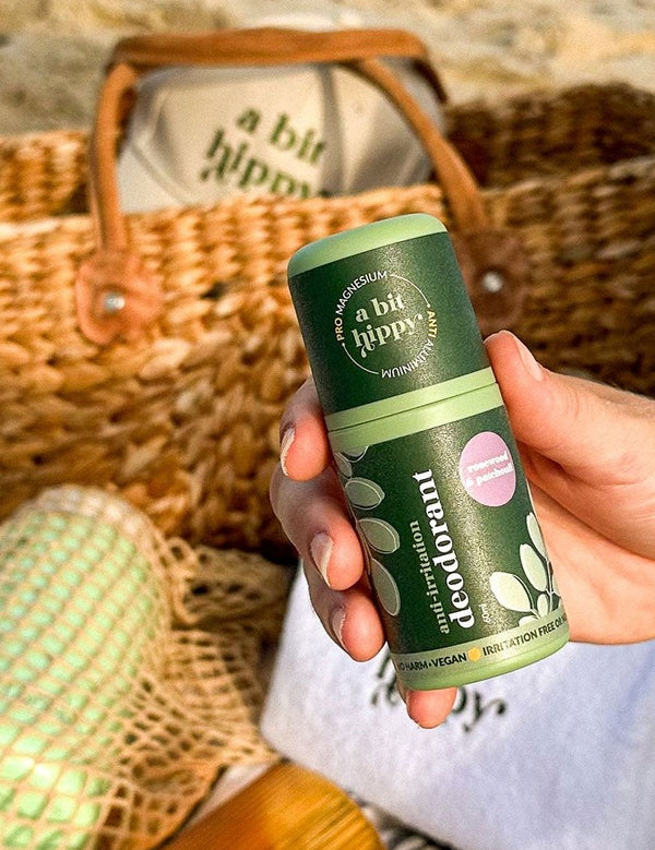 A bit Hippy Patchouli Deodorant held outdoors beside a beach bag