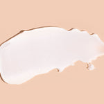 A broad white swatch of A bit Hippy Face Cream spread horizontally on peach, with a smooth centre, a rounded left end and an uneven, tapered right edge.