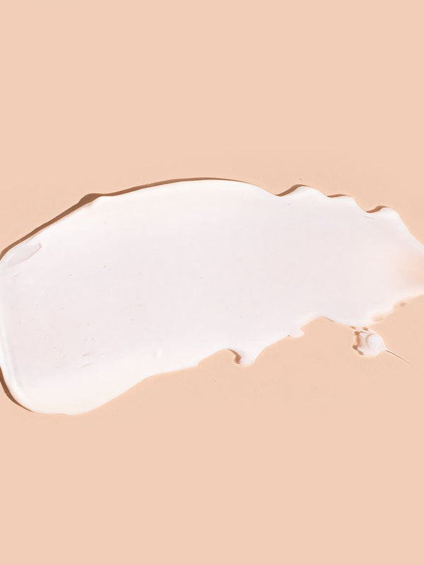 A broad white swatch of A bit Hippy Face Cream spread horizontally on peach, with a smooth centre, a rounded left end and an uneven, tapered right edge.