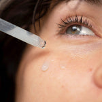 Woman applying Ere Perez White Tea Phyto-Retinol Elixir to her cheek with the dropper