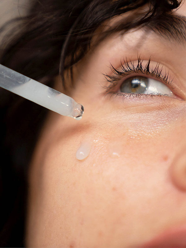 Woman applying Ere Perez White Tea Phyto-Retinol Elixir to her cheek with the dropper