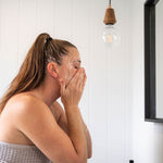 Woman washing her face at the bathroom mirror with Mukti Balancing Cleansing Gel