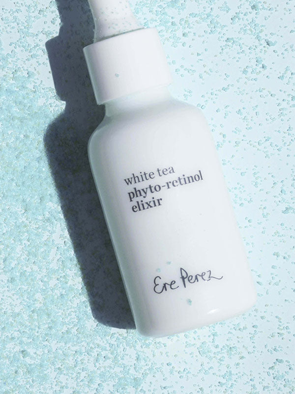Ere Perez White Tea Phyto-Retinol Elixir bottle lying among scattered pale blue crystals