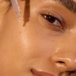 Close-up face applying ACURE Argan Oil with a dropper