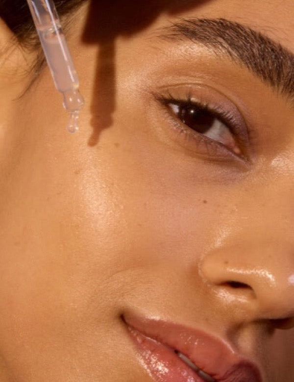 Close-up face applying ACURE Argan Oil with a dropper