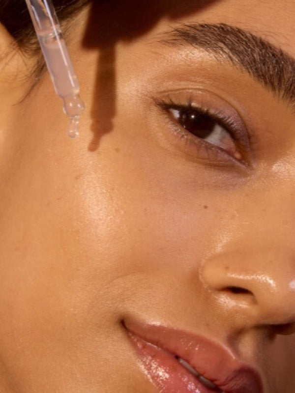 Close-up face applying ACURE Argan Oil with a dropper