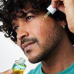 Model applying Acure Dual Phase Bakuchiol Serum to the cheek with a glass dropper.