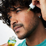 Model applying Acure Dual Phase Bakuchiol Serum to the cheek with a glass dropper.