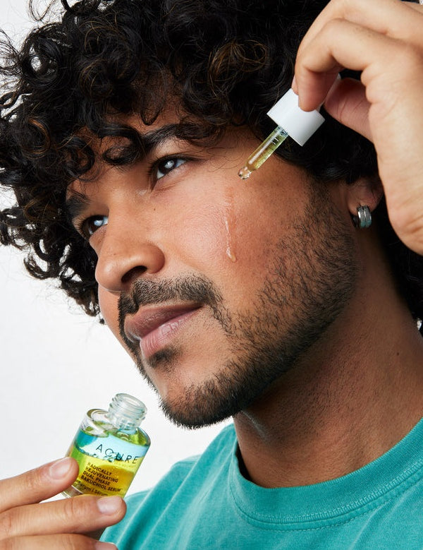 Model applying Acure Dual Phase Bakuchiol Serum to the cheek with a glass dropper.