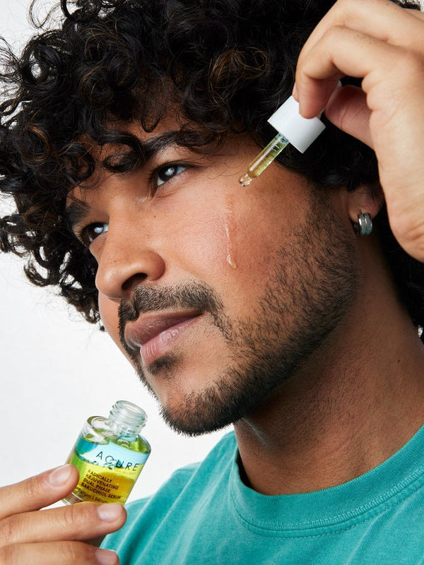 Model applying Acure Dual Phase Bakuchiol Serum to the cheek with a glass dropper.