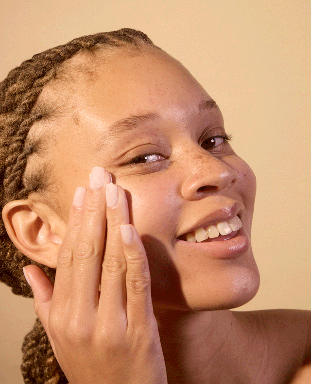 Woman applying ACURE Brightening Day Cream to her face