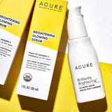 Two boxes and a pump bottle of Acure Brightening Glowing Serum 30ml, all in yellow and white packaging, are displayed against a matching background—ideal for anyone looking to boost skin radiance.