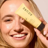 Model holding ACURE Brightening Night Cream beside her face