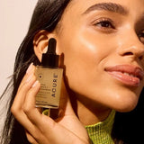 Model holding ACURE Brightening 2% Vitamin C & Ferulic Acid Serum beside her face