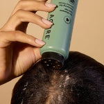 Brunette model applying ACURE Dry Shampoo directly to her roots
