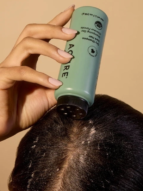 Brunette model applying ACURE Dry Shampoo directly to her roots