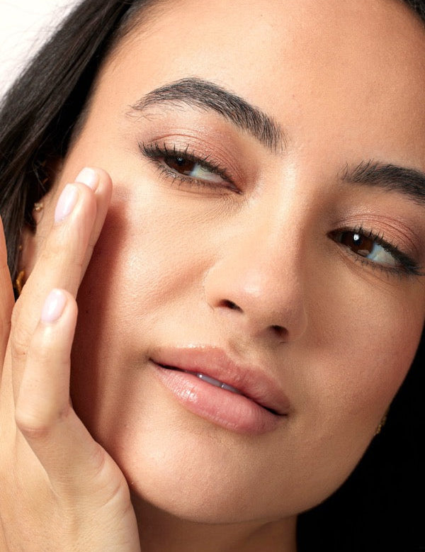 Close-up face applying ACURE Radically Rejuvenating Eye Cream