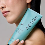 Model holding a tube of ACURE Ultra Hydrating Shampoo