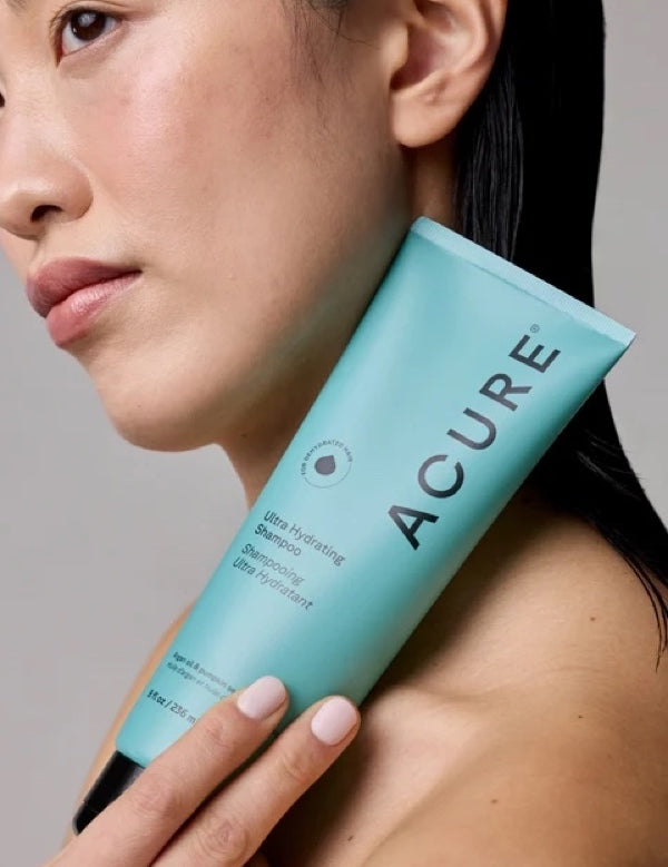 Model holding a tube of ACURE Ultra Hydrating Shampoo