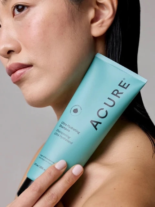 Model holding a tube of ACURE Ultra Hydrating Shampoo