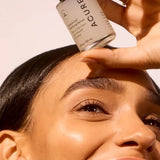 Model holding ACURE Zombie Cell Clarifying Serum beside her face