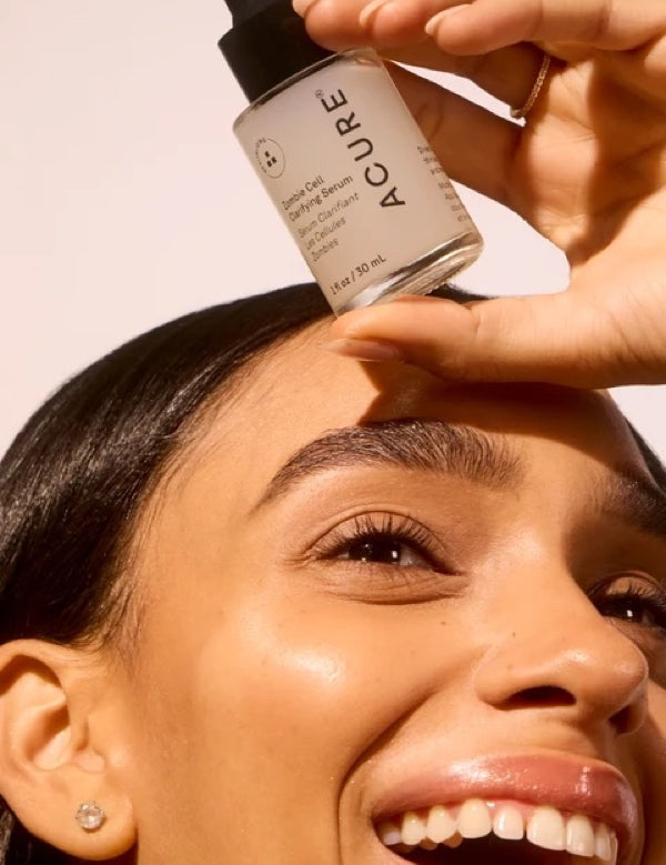 Model holding ACURE Zombie Cell Clarifying Serum beside her face