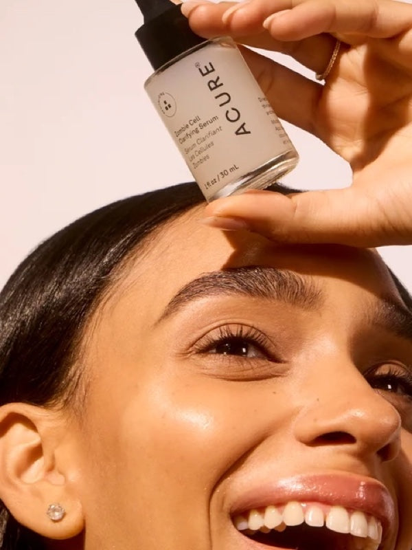 Model holding ACURE Zombie Cell Clarifying Serum beside her face