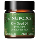 Antipodes Kiwi Seed Oil Eye Cream in an amber glass jar with a green label, gold botanical details and a wide black lid, on white.