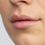 Close-up of the lower half of a person's face showing smooth skin with a natural complexion and some freckles. Their lips appear soft and supple, thanks to Antipodes Kiwi Seed Oil Lip Conditioner 4g.