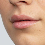 Close-up of the lower half of a person's face showing smooth skin with a natural complexion and some freckles. Their lips appear soft and supple, thanks to Antipodes Kiwi Seed Oil Lip Conditioner 4g.