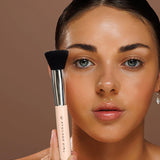 Model holding the Avocado Zinc SPF Kabuki Brush upright against her cheek.