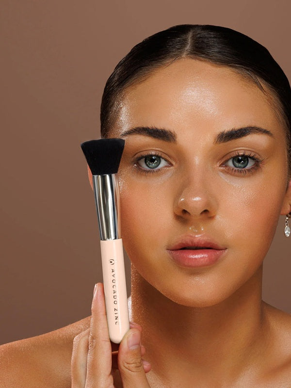 Model holding the Avocado Zinc SPF Kabuki Brush upright against her cheek.