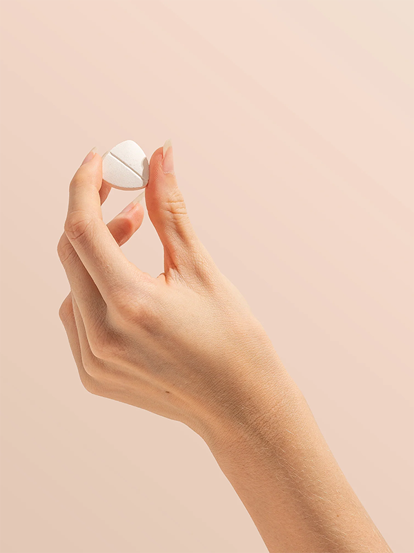 Hand holding a Herbs of Gold Magnesium Chewable raspberry tablet