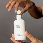 Hands dropping an Ere Perez Ginkgo Micellar Cleanser tablet into the refillable white bottle