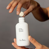 Hands dropping an Ere Perez Ginkgo Micellar Cleanser tablet into the refillable white bottle
