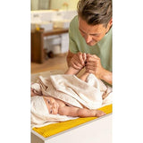 Baby wrapped in a towel and male parent holding his feet.