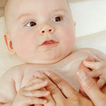 Baby lying down with parents arms on the belly.