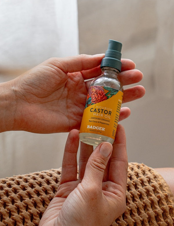 Badger Castor Hair Oil held in both hands