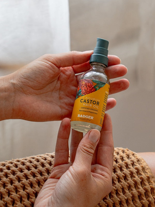 Badger Castor Hair Oil held in both hands