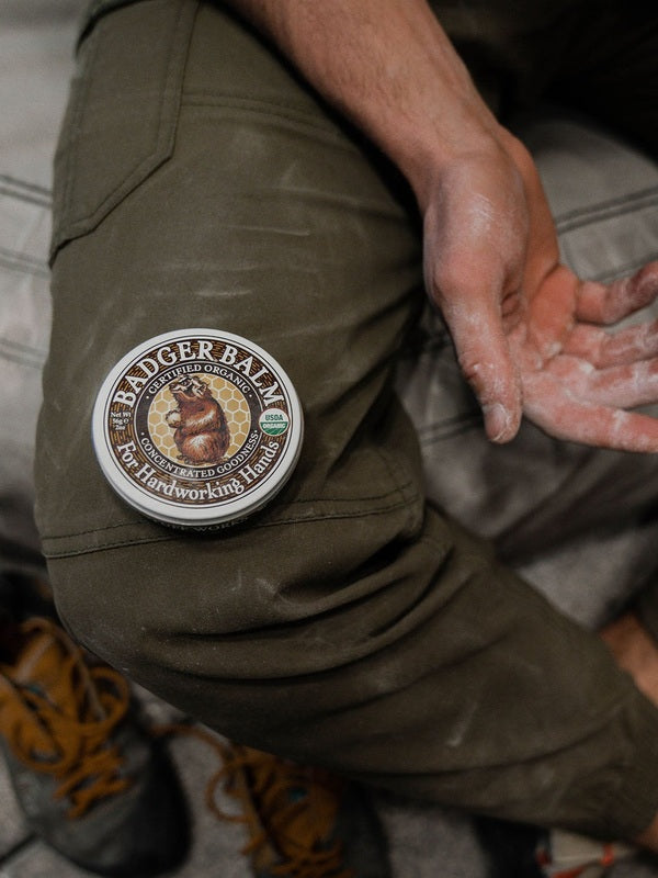 Badger Hardworking Hands Balm beside work-worn hands