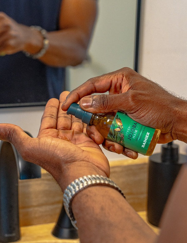 Badger Jojoba Hair Oil dispensed into a hand