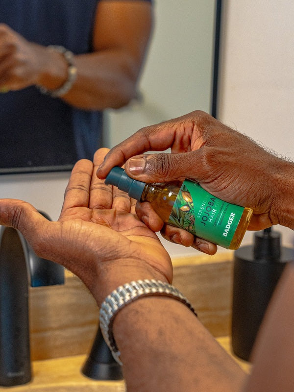 Badger Jojoba Hair Oil dispensed into a hand