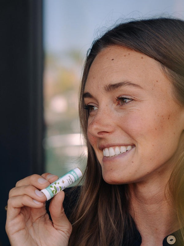 Woman applying Badger Highland Mint Lip Balm