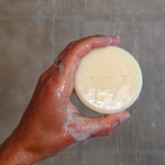 Badger Shampoo Bar held under running shower water