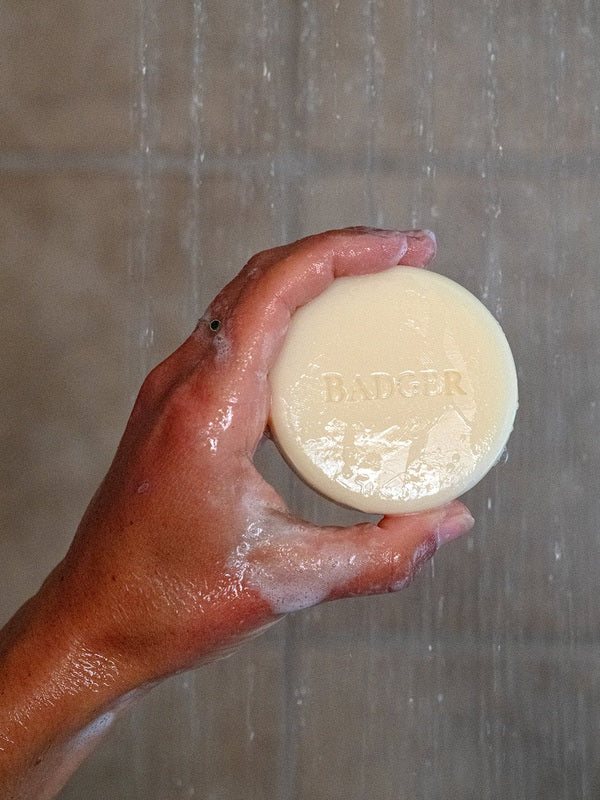 Badger Shampoo Bar held under running shower water