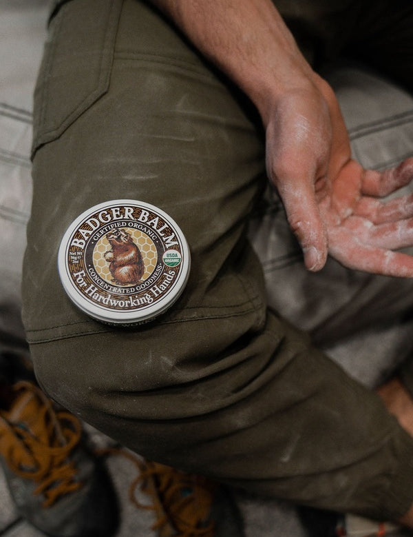 Badger Unscented Healing Balm beside work-worn hands