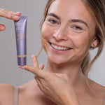Smiling model holding a tube of Benecos BB Cream beside her face.
