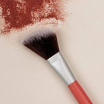 Benecos Blush Brush arranged diagonally across crushed warm red blush pigment.