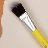 Benecos Foundation Brush with yellow handle arranged diagonally on a neutral cream background with terracotta shapes.